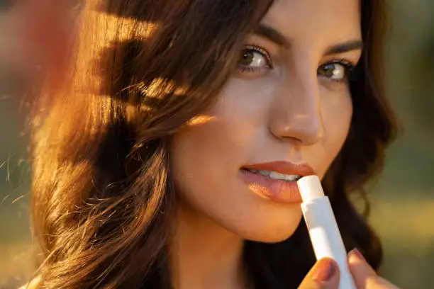 Pretty natural, feminine woman applying lip balm on her lips