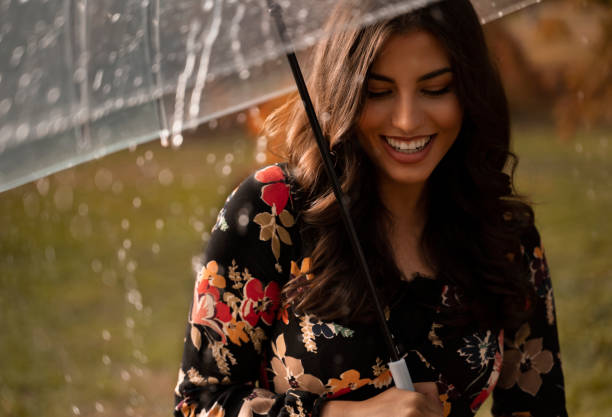 istock Beautiful girl holding translucent umbrella while raining and smiling 1182556153