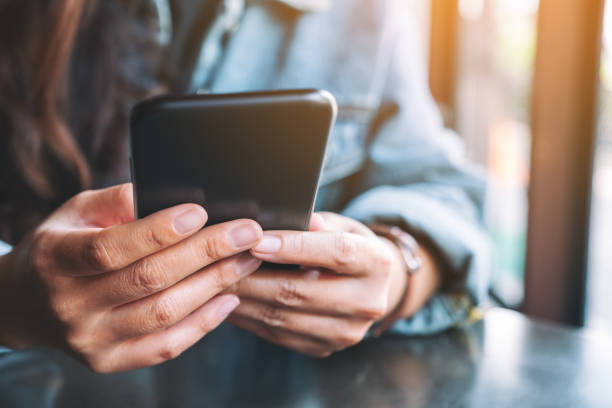istock a woman holding, using and looking at mobile phone 1182564567