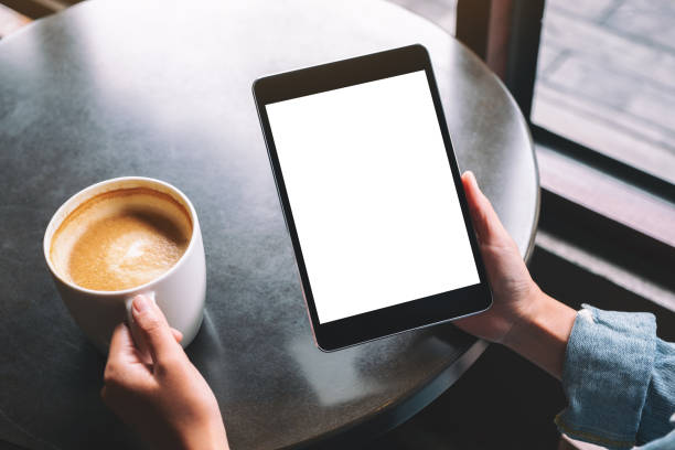 istock a woman holding black tablet with white blank desktop screen while drinking coffee 1182565098