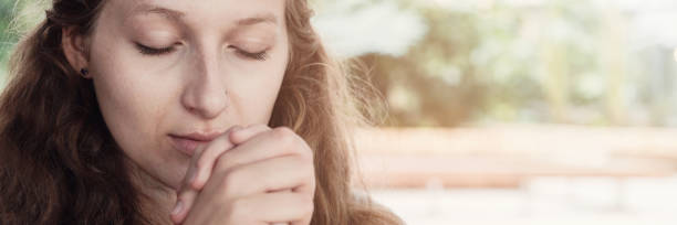 istock Young woman praying with eyes closed 1182565553