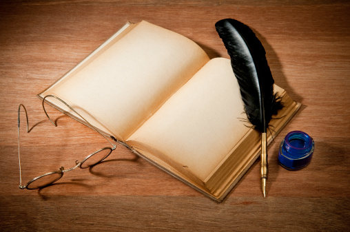 Old blank book with quill pen, ink well and glasses.