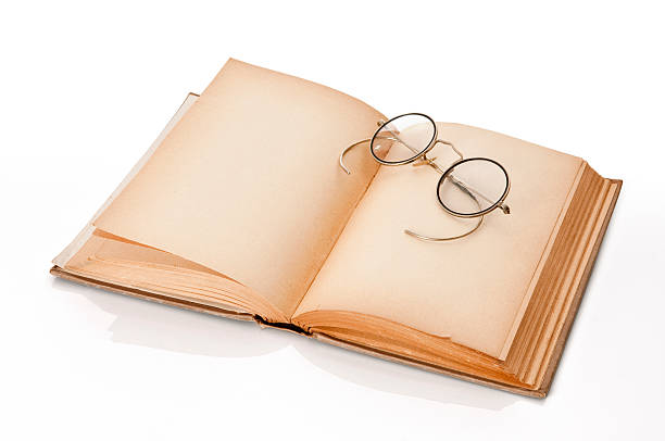 Close up of glasses lying on an open book with natural sunlight. Working from home. Freelance. Self-employment concept