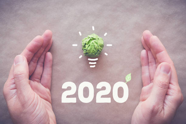 istock Hands with 2020 Green paper light bulb, New year eco, social responsibility, csr, innovation solution concept 1182568227