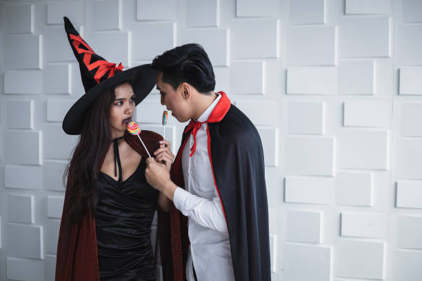 istock Asian young couple in costume witch and dracula on white wall. 1182570840
