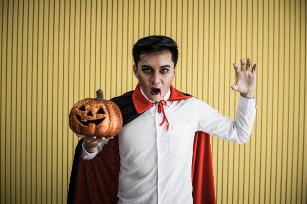 istock Young Asian man in costume dracula on yellow background. 1182570896