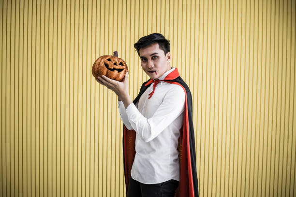 istock Young Asian man in costume dracula on yellow background. 1182570909