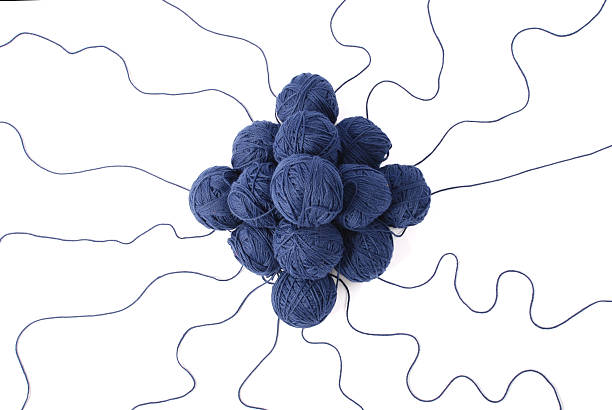 Close shot of a skein of blue colored wool yarn on a wood background