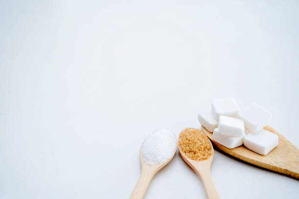 istock White sugar, brown sugar, sugar cubes, placed in a wooden spoon. 1182573974