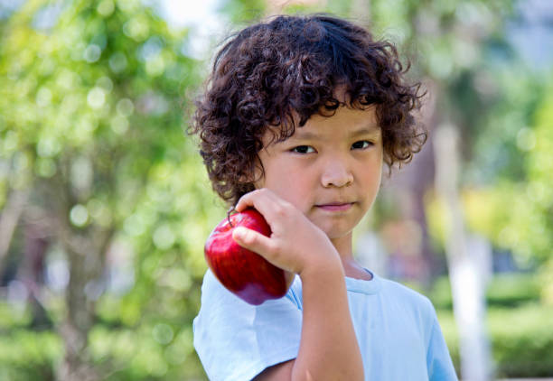 istock Little boy with apple outdoors 1182574595