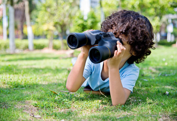 istock Little boy holding a binocular at park 1182574603