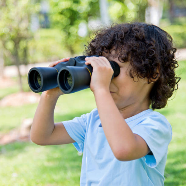 istock Little boy holding a binocular at park 1182574616