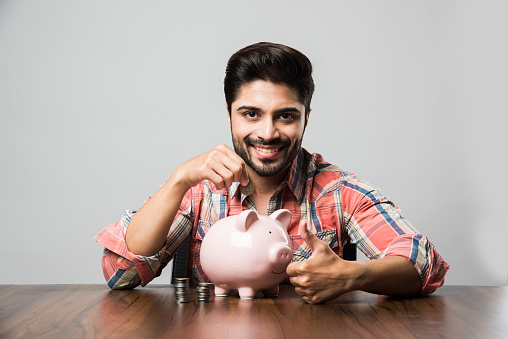 Indian Man with Piggy Bank, sitting at table