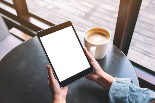 istock a woman holding black tablet with white blank screen and coffee cup on the table 1182576271