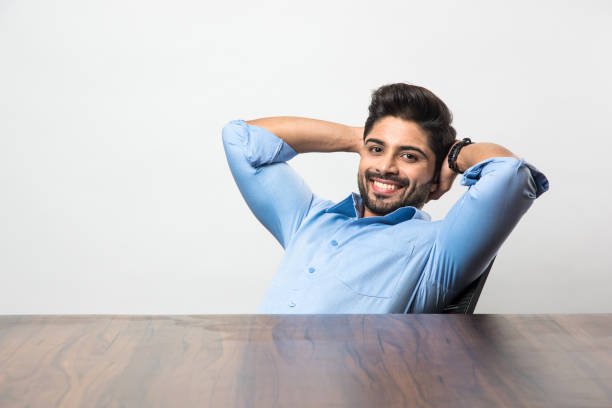 Indian businessman relaxing / stretching  at workstation in office