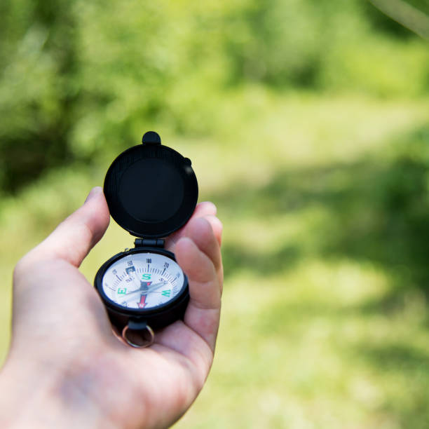 Hand holding a compass outdoors.