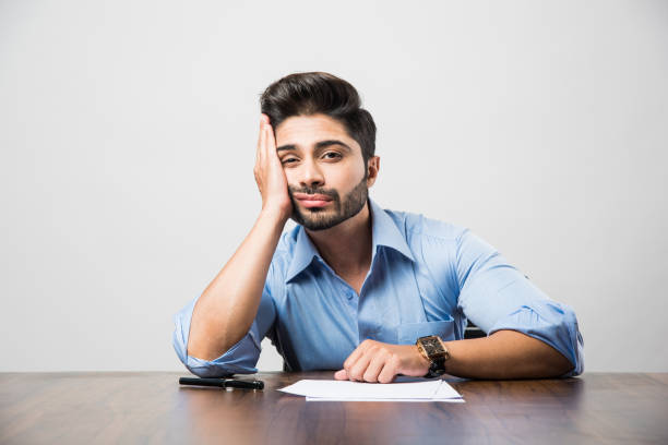 istock Stressed Indian Businessman having headache or Migraine pain while working at office table 1182584294
