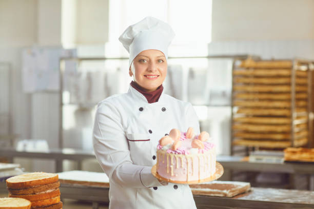 istock Confectioner with pastry cake in his hand at the bakery. 1182585117
