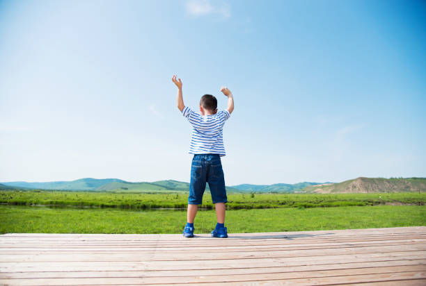 Little boy with arms raised outdoors
