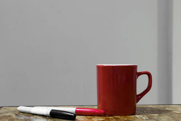 Red mug and pens over the desk at the office