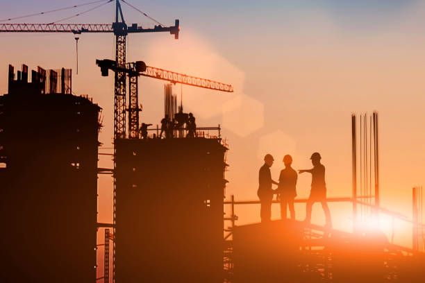 istock Silhouette Two engineers consult and inspect high-rise construction work over blurred industry background with Light fair.Create from multiple reference images together 1182593735