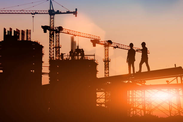 istock Silhouette Two engineers consult and inspect high-rise construction work over blurred industry background with Light fair.Create from multiple reference images together 1182593745