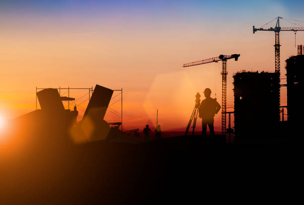 istock Silhouette of Survey Engineer and construction team working at site over blurred  industry background with Light fair.Create from multiple reference images together 1182593754