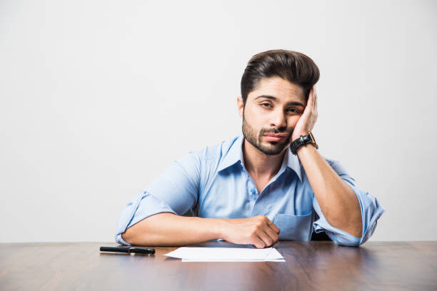 stressed indian businessman having headache or migraine pain while working at office table - gesturing imagens e fotografias de stock