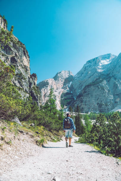 istock young man with backpack walking by mountains trail in sunny day summer activities 1182594183