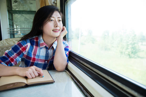 istock Young asian woman reading book on a train 1182595430