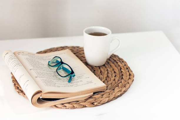 istock open book and glasses, lemon tea in a white ceramic cup on a wicker stand on the table, cozy home interior 1182597516