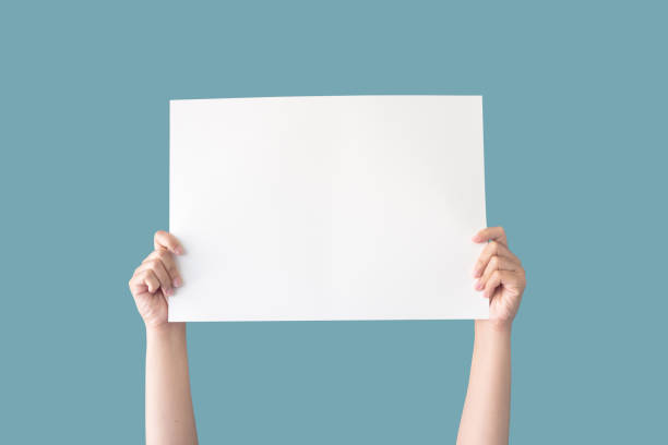 hand hält weißes, leeres papier isoliert auf blauem hintergrund mit clipping-pfad - man holding a sign stock-fotos und bilder