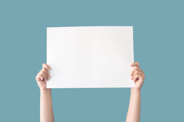 mano sosteniendo blanco papel en blanco aislado en el fondo azul con el camino de recorte - señal fotografías e imágenes de stock