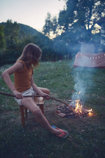 Small child girl making campfire on a lawn.