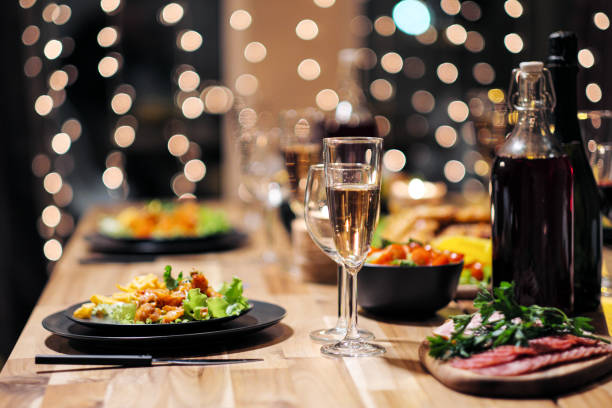 Festive table setting. Food and drinks, plates and glasses. Evening lights and candles. New Year's Eve. stock photo