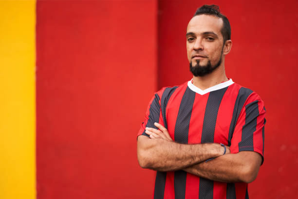 istock Football player pose on red background with arms crossed 1182604730