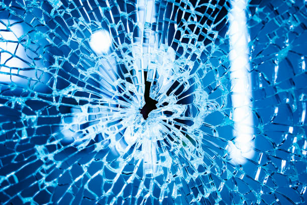 Broken glass window. Broken glass window. Blue background. Closeup. Shot in a glass. gebrochen stock pictures, royalty-free photos & images