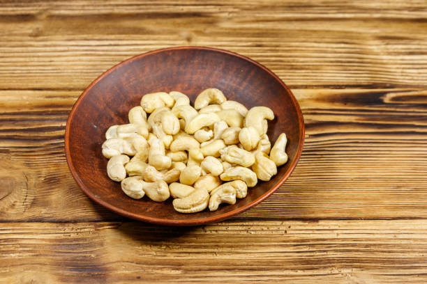 istock Ceramic plate with raw cashew nuts on a wooden table 1182606396