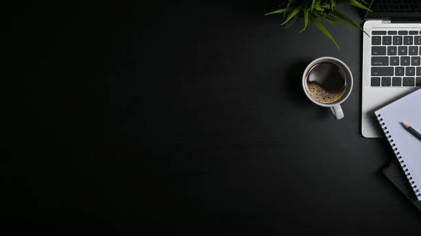 istock Copy space office black table with laptop, notebook, pencil and coffee cup with plat. 1182608771