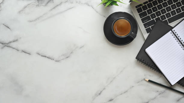 istock Top view office desk marble table with  laptop, notebook paper, pencil and espresso coffee. 1182608772