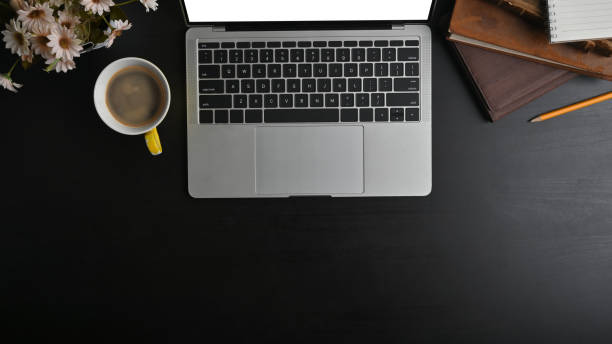 istock Top view mockup laptop, notebook, pencil and coffee with flower on black table. 1182609185