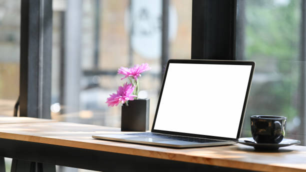 istock Open blank screen laptop computer in comfortable workspace with flower pot. 1182610239