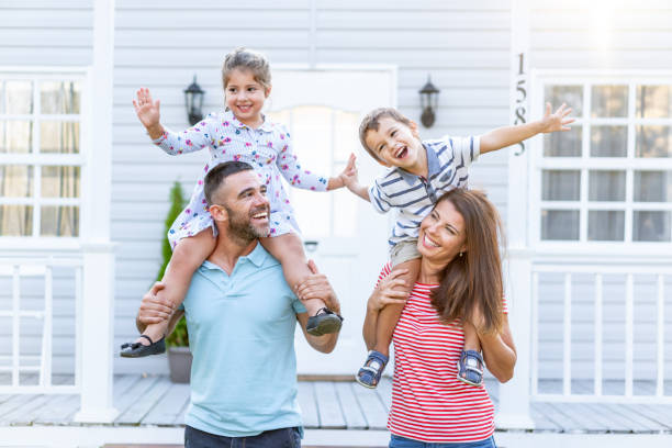 istock Parents having fun in front yard carrying children piggyback 1182611491