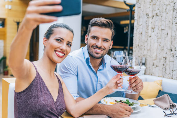 istock Couple dining and drinking red wine in restaurant and taking selfie 1182613436