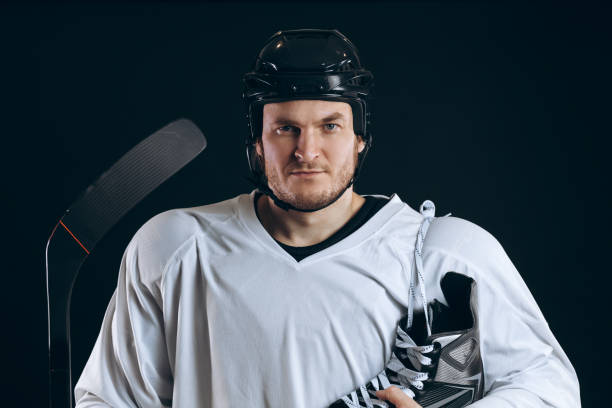 istock Handsome hockey player. Smiling at camera isolated on black background. 1182614356