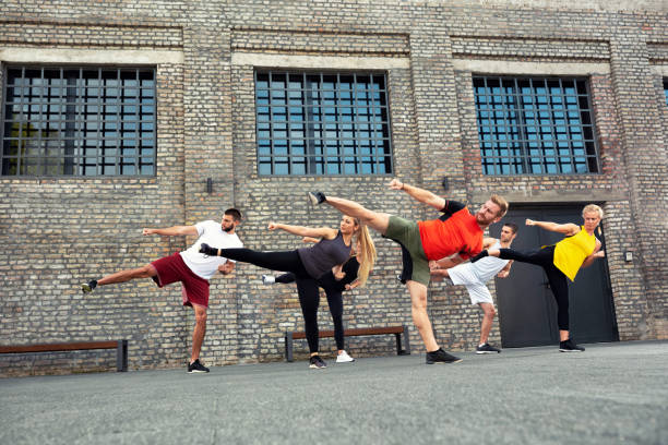 Sport enthusiasts exercising leg kicks in front of a brick wall