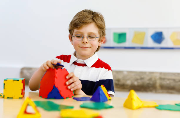 istock Happy kid boy with glasses having fun with building and creating geometric figures, learning mathematics and geometry 1182619368