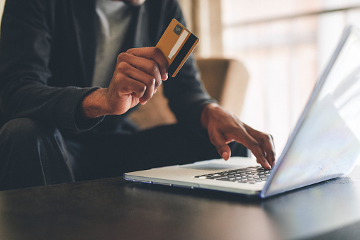 Cropped shot of an unrecognizable man using a credit card and a laptop to shop online at home