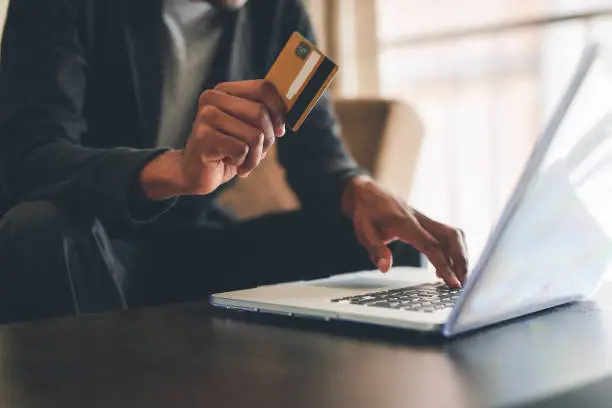 Cropped shot of an unrecognizable man using a credit card and a laptop to shop online at home