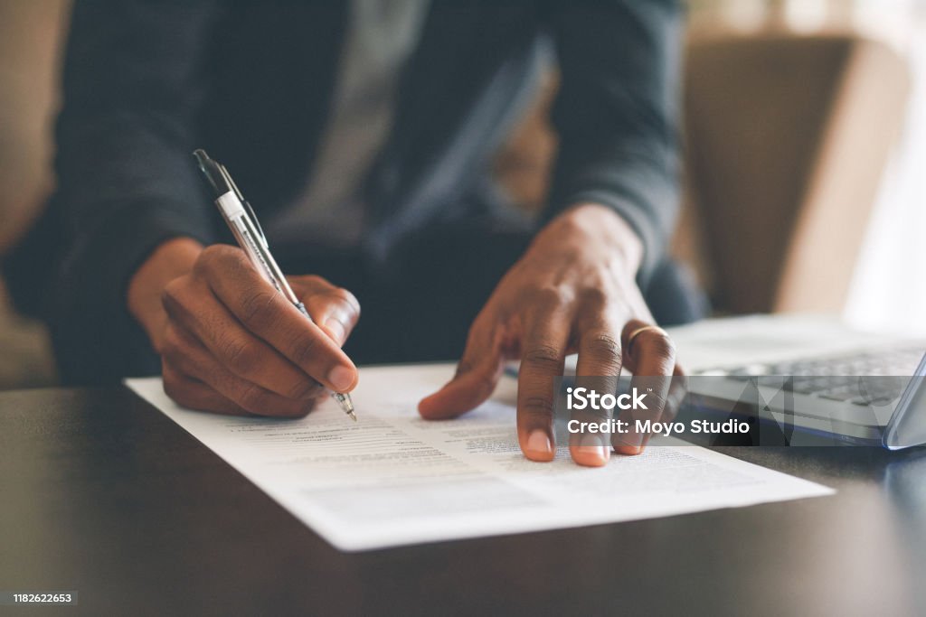 He's doesn't play when it comes to his budget Cropped shot of an unrecognizable man filling out paperwork while doing his budget at home Form - Document Stock Photo